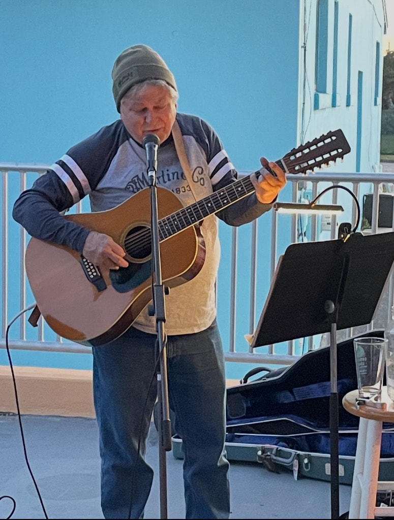 Guy Savino performing outdoors with 12-string acoustic guitar